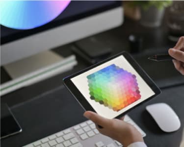 Desktop view with tablet, unknown user holding the tablet, mouse and keyboard on desk.